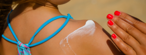 Young child at the beach receiving sunscreen application by adult